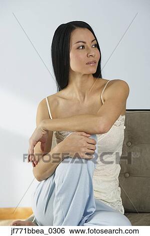 Asian woman sitting on sofa View Large Photo Image Stock Photograph - Asian woman sitting on sofa. Fotosearch