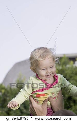 Stock Image - Baby being held up outdoors. Fotosearch
