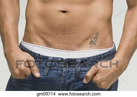 Picture - Bare-chested Hispanic man with hands in pockets. Fotosearch