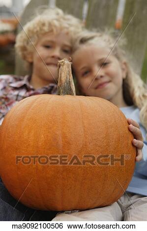 Stock Photograph - Brother and sister holding pumpkin. Fotosearch