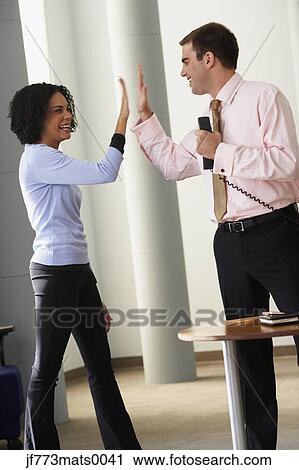 Stock Image - Businessman and businesswoman high-fiving. Fotosearch