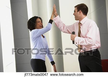 Stock Photo - Businessman and businesswoman high-fiving. Fotosearch