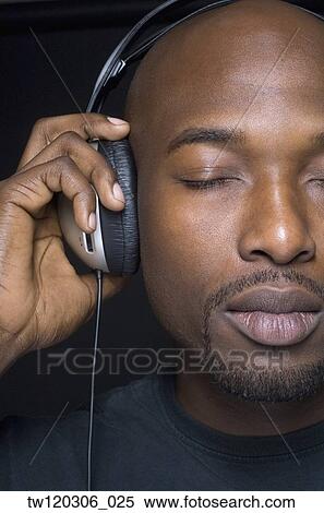 Stock Photography - Close up of African man wearing headphones. Fotosearch