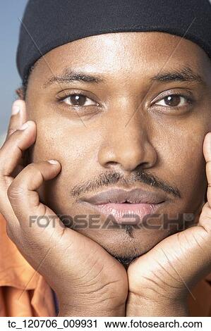 Stock Image - Close up of African man with chin in hands. Fotosearch