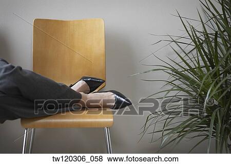 Stock Photo - Close up of businesswoman’s feet on chair. Fotosearch