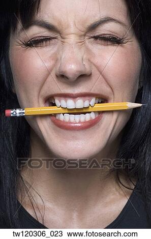 Stock Image - Close up of woman biting pencil. Fotosearch