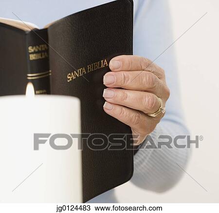 Stock Image - Close up of woman holding Spanish bible. Fotosearch