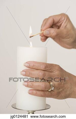 Stock Image - Close up of woman lighting candle. Fotosearch