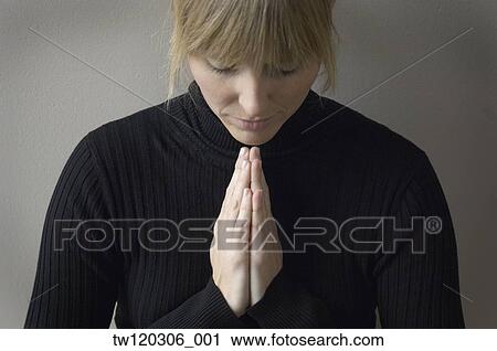 Stock Image - Close up of woman praying. Fotosearch