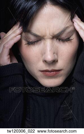 Stock Image - Close up of woman rubbing temples. Fotosearch