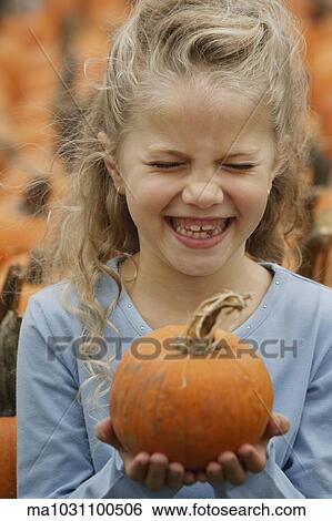 Girl laughing and holding pumpkin View Large Photo Image Stock Photograph - Girl laughing and holding pumpkin. Fotosearch