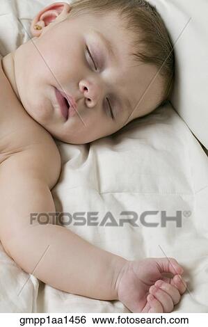 Stock Photograph - Hispanic baby sleeping on bed. Fotosearch