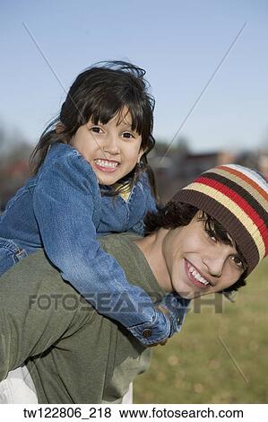 Stock Photo - Hispanic boy giving sister piggyback ride. Fotosearch