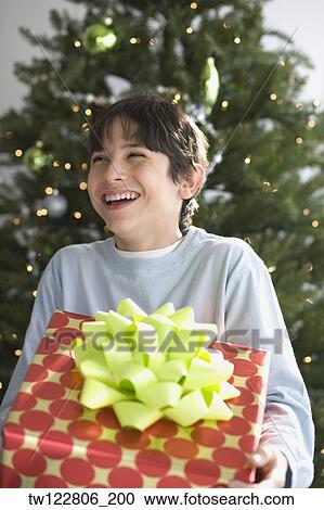 Stock Image - Hispanic boy holding Christmas gift. Fotosearch