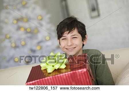 Hispanic boy holding Christmas gift View Large Photo Image Stock Photo - Hispanic boy holding Christmas gift. Fotosearch