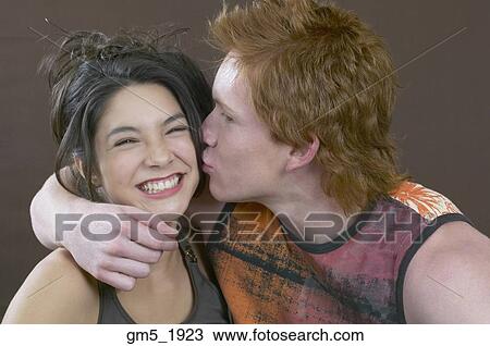 Stock Image - Hispanic brother kissing sister on cheek. Fotosearch