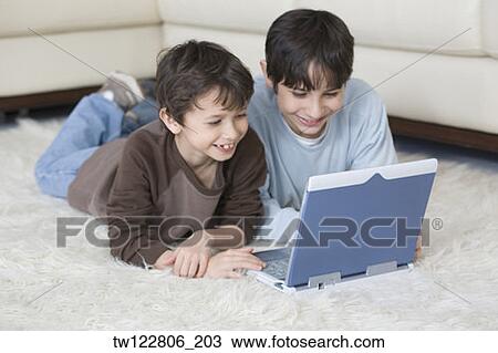 Hispanic brothers looking at laptop View Large Photo Image Stock Image - Hispanic brothers looking at laptop. Fotosearch