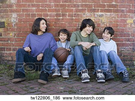 Stock Photograph - Hispanic brothers sitting with basketball. Fotosearch