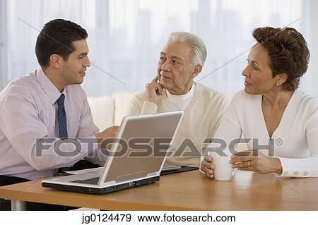 Hispanic businessman talking to senior couple in home View Large Photo Image Stock Photo - Hispanic businessman talking to senior couple in home. Fotosearch