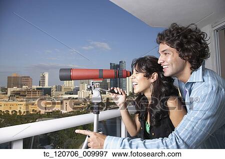 Hispanic couple looking through telescope on balcony View Large Photo Image Stock Photo - Hispanic couple looking through telescope on balcony. Fotosearch