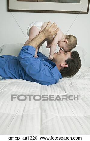 Stock Image - Hispanic father playing with baby. Fotosearch
