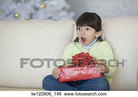 Stock Photograph - Hispanic girl holding Christmas gift. Fotosearch