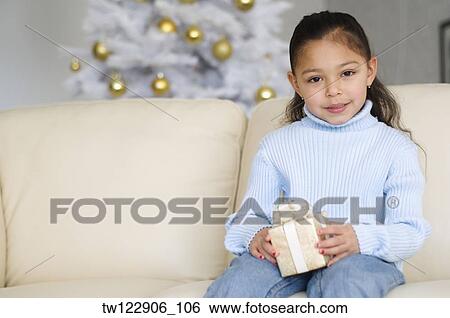 Hispanic girl holding Christmas gift View Large Photo Image Stock Photograph - Hispanic girl holding Christmas gift. Fotosearch
