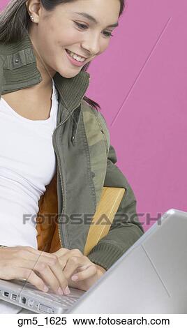 Stock Photography - Hispanic girl typing on laptop. Fotosearch