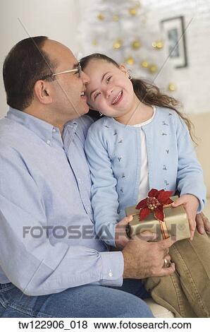 Stock Photo - Hispanic grandfather giving gift to granddaughter. Fotosearch