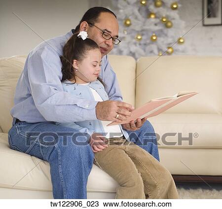 Stock Image - Hispanic grandfather reading to granddaughter. Fotosearch