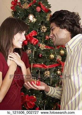 Hispanic man giving girlfriend Christmas gift View Large Photo Image Stock Photo - Hispanic man giving girlfriend Christmas gift. Fotosearch
