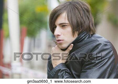 Stock Image - Hispanic man holding jacket closed. Fotosearch
