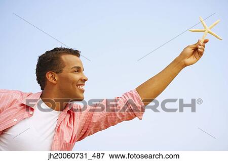 Hispanic man holding starfish View Large Photo Image Stock Photo - Hispanic man holding starfish. Fotosearch