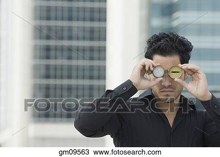 Hispanic man holding watch over eyes View Large Photo Image Stock Image - Hispanic man holding watch over eyes. Fotosearch