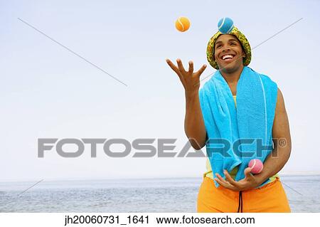 Stock Image - Hispanic man juggling at beach. Fotosearch