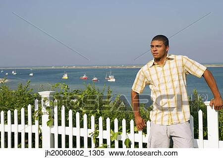 Stock Photography - Hispanic man leaning against fence. Fotosearch