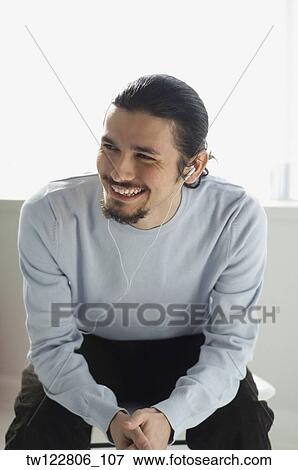 Stock Photo - Hispanic man listening to mp3 player. Fotosearch