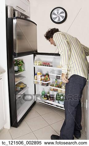 Hispanic man looking in refrigerator View Large Photo Image Stock Photography - Hispanic man looking in refrigerator. Fotosearch