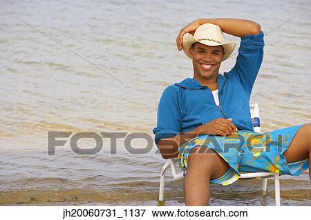 Hispanic man sitting in beach chair View Large Photo Image Stock Photo - Hispanic man sitting in beach chair. Fotosearch