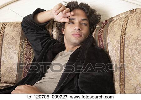 Stock Photo - Hispanic man sitting on bed. Fotosearch