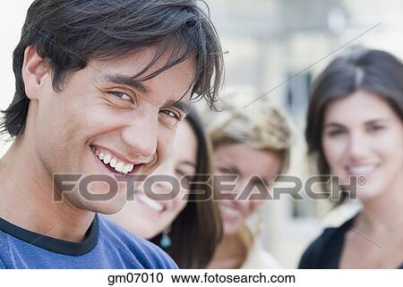 Hispanic man smiling with friends in background View Large Photo Image Stock Image - Hispanic man smiling with friends in background. Fotosearch