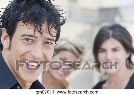 Hispanic man smiling with friends in background View Large Photo Image Stock Image - Hispanic man smiling with friends in background. Fotosearch