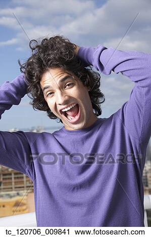 Stock Image - Hispanic man with hands in hair. Fotosearch