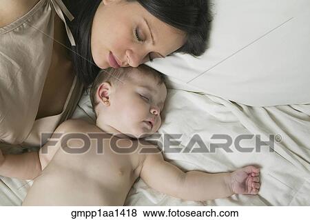 Stock Photo - Hispanic mother and baby sleeping on bed. Fotosearch
