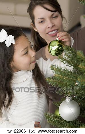 Hispanic mother and daughter decorating Christmas tree View Large Photo Image Stock Photography - Hispanic mother and daughter decorating Christmas tree. Fotosearch