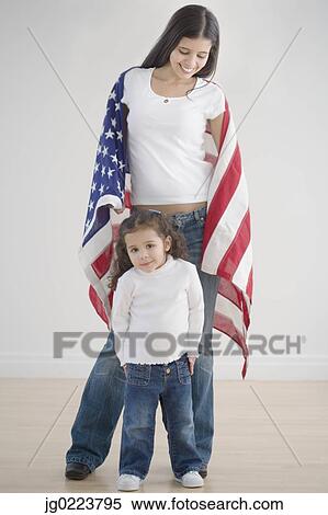 Stock Photography - Hispanic mother and daughter holding American flag. Fotosearch