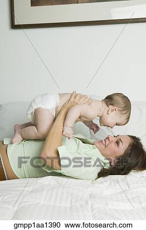 Stock Image - Hispanic mother playing with baby. Fotosearch