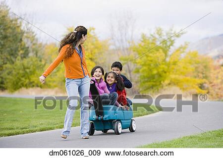 Hispanic mother pulling children in wagon View Large Photo Image Stock Photo - Hispanic mother pulling children in wagon. Fotosearch