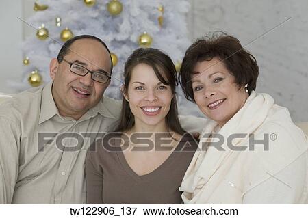 Hispanic parents and adult daughter next to Christmas tree View Large Photo Image Stock Photo - Hispanic parents and adult daughter next to Christmas tree. Fotosearch