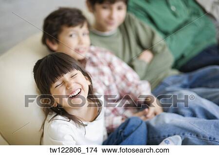 Hispanic siblings sitting on sofa View Large Photo Image Picture - Hispanic siblings sitting on sofa. Fotosearch
